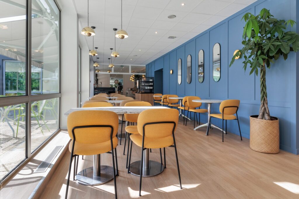 Restaurant-lounge aux chaises jaunes le long des baies vitrées